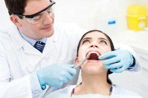 Dentist taking a closer look as patient leans back and opens mouth for annual teeth cleaning